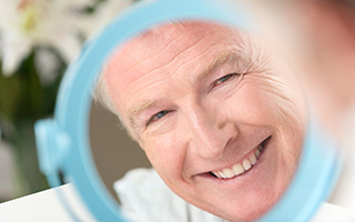 Senior man looking at smile in mirror