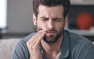 Man holding jaw in pain